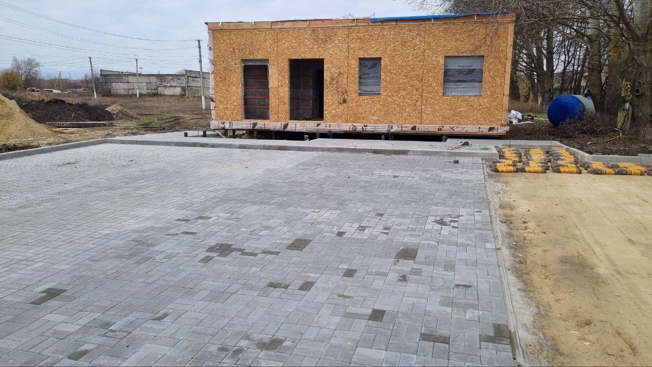 Вокруг ФАПа в Морозовке проводится благоустройство территории Костромские строители продолжают возводить новый ФАП в небольшом меловском поселке Морозовка Строительство ведется в рамках инфраструктурного проекта по запросу Меловской стороны Быстровозводимая конструкция ФАПа строится по современной каркасной технологии что позволяет закончить объект в короткие сроки примерно за один сезон Уже собран и установлен домокомплект здания Следующий этап установка крыши окон и дверей а затем монтаж входной группы крыльца В данный момент завершаются работы по благоустройство прилегающей к ФАПу территории Площадку выкладывают плиткой устанавливают бордюры разбивают клумбы на которых весной будут высажены цветы и кустарники Параллельно с этим проводятся работы по прокладке наружных коммуникаций уже сделана скважина для забора воды выполнен подвод воды в здание установлен септик Сухая и теплая погода позволяет проводить работы без отставания от графика