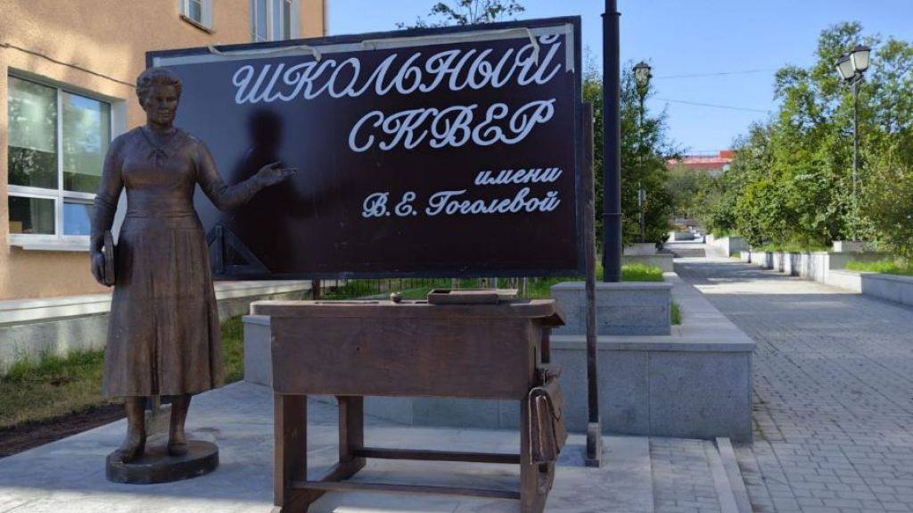 Новый памятник учителю украсил сквер в Магадане 25 августа у входа в сквер 60 летия Магадана была установлена скульптурная композиция из бронзы изображающая учителя рядом со школьной доской и партой Автором работы стал народный художник России Константин Кузьминых который задумал памятник три года назад во время реконструкции сквера Он выбрал участок между театром и домом быта Заря для создания главного оформленного входа Фигура учителя выполненная в полный рост воплощает черты Веры Ефимовны Гоголевой известного педагога ставшего прототипом скульптуры В одной руке она держит папку а другая полусогнута в объясняющем жесте что символизирует процесс обучения На школьной доске написано Школьный сквер имени В Е Гоголевой что подчеркивает связь с её образом хотя название сквера остается прежним