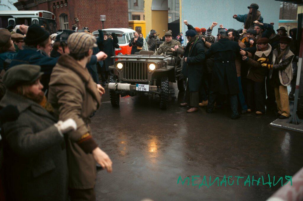 На стримингах Premier и KION стартовал необычный исторический мини сериал Дорогой Вилли четырехсерийный гибрид шпионского триллера и политической фантасмагории от Игоря Прокопенко Проект сразу заявляет о своей особости это альтернативная история где Генсек ЦК КПСС Леонид Брежнев и канцлер ФРГ Вилли Брандт объединяются чтобы предотвратить ядерную войну между СССР и США в конце 1960 х Прокопенко известный своими сенсационными расследованиями на Рен ТВ настаивает на абсолютной правдивости истории ссылаясь на архивы и интервью с участниками событий Однако зрителя ждет не сухая хроника а увлекательный почти сказочный эскапизм Сериал сознательно создает теплый лампово советский мир где даже у геополитического противостояния должен быть счастливый конец Это не недостаток а сознательная авторская позиция дать зрителю ту версию прошлого в которую хочется верить Безусловным открытием сериала становится Евгений Маковецкий в роли Леонида Брежнева Актер играет молодого ироничного и мудрого стратега практически без грима делая ставку на обаяние и интеллект После гротескного образа в исполнении Виктора Стоянова в Играх этот Брежнев действительно отдохновение Он травит анекдоты милуется с актерами Кабачка 13 стульев и с легкостью переигрывает своего идеологического оппонента Суслова которого к слову великолепно играет вернувшийся в кино Владимир Конкин Канва разворачивается вокруг реального исторического факта планов США по размещению ядерных ракет в ФРГ Узнав об этом Брежнев и Андропов отправляют в Западный Берлин двух журналистов германистов блестящий дуэт Сергея Марина и Алексея Розина с заданием тайно предупредить Брандта убедительный Кирилл Кяро Далее следуют классические шпионские страсти перестрелки красивые женщины и двойные игры При этом создатели подчеркивают что у главных героев есть реальные прототипы что добавляет истории пикантности Дорогой Вилли это смелый и очаровательный эксперимент Он не претендует на звание учебника истории зато предлагает зрителю уютный стилизованный мир где враги могут стать союзниками а угроза ядерной войны отступает перед человеческой мудростью и юмором Это идеальный сериал для тех кто хочет на пару часов сбежать от суровой реальности в альтернативные шестидесятые какими они возможно могли бы быть Кинокритик Анна Журба специально для mediastanciacom