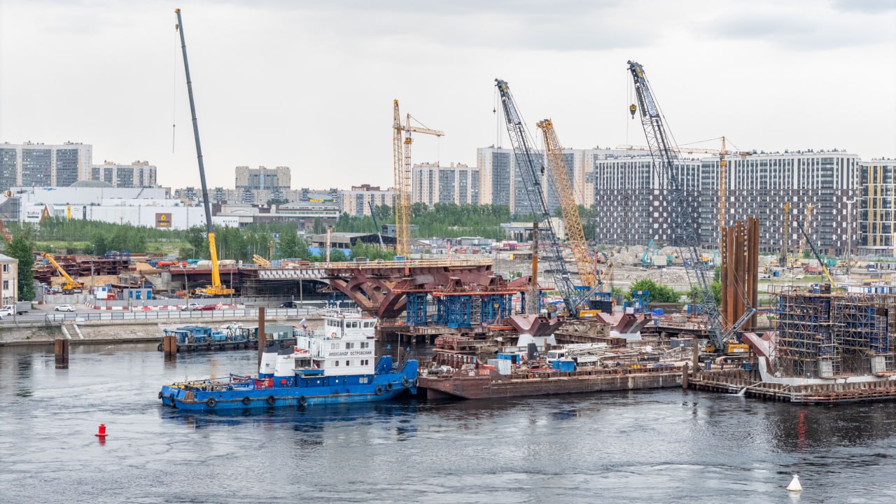 На опоре №5 строящегося Большого Смоленского моста смонтирована система из четырех гидроцилиндров. Это важный элемент механизма разводного пролета.  Каждое устройство весит порядка 6 тонн. Их монтировали с помощью крана, установленного на барже. Они способны выдержать расчетную нагрузку 360 тонн для разводки и 300 тонн для сведения разводного пролета. На опоре заранее забетонировали элементы опорных узлов гидроцилиндров и смонтированы противовесные блоки. Впоследствии они уравновесят пролетное строение и обеспечат функционирование «крыльев» моста.  На опоре №6 в III квартале установят еще четыре гидроцилиндра.  На пятой и шестой опорах Большого Смоленского моста будет располагаться двукрылый разводной пролет шириной 60 м. Он обеспечит регулярный пропуск судов.  Сборка металлоконструкций разводного пролета продолжается на стапеле Перевозной набережной. После завершения навигации планируется при помощи барж переместить разводной пролет на опоры.  Фото: правительство Петербурга/gov.spb.ru