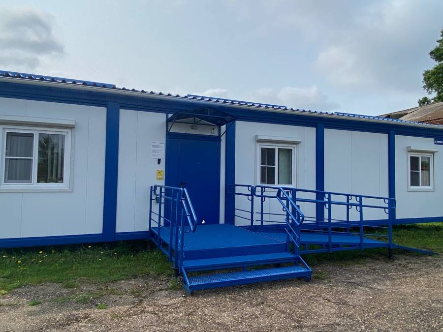 В селе Почитанка Ижморского муниципального округа открылся новый ФАП На строительство и оснащение ФАПа по нацпроекту «Продолжительная и активная жизнь», инициированному Президентом России Владимиром Путиным, было направлено 7,6 млн рублей. Теперь более 150 человек, в том числе 25 детей, смогут получать медицинскую помощь в комфортных условиях рядом с домом. Ранее ФАП располагался в здании двухквартирного дома. Теперь в новом модульном здании предусмотрены все необходимые помещения: кабинет для приема врача, прививочный и процедурный, а также зона ожидания. В просторных помещениях с комфортом смогут разместиться как медики, так и пациенты. Для удобства маломобильных граждан оборудованы пандусы и установлены кнопки вызова персонала.