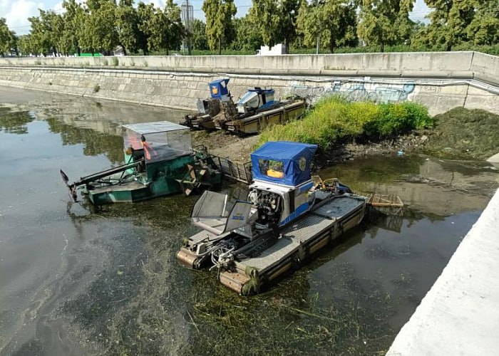 На реке Миасс в Челябинске появятся острова из водорослей и ила В Челябинске возобновили очистку реки Миасс от ила и водорослей. Для этого на воду спустили сразу пять многофункциональных машин. Техника косит подводную растительность, которую потом можно будет легко собрать. Сейчас специалисты работают на участке реки от улицы Энгельса до недостроенного конгресс-холла. С помощью косилок и граблей-коллекторов они срезают подводные и надводные растения и собирают их вместе с прочим мусором. Это происходит не сразу, поэтому скоро челябинцы могут заметить на реке плавучие острова из водорослей, травы и ила. – Не стоит волноваться — это часть запланированных работ. Вся скошенная растительность скоро будет удалена, а жители и гости южноуральской столицы смогут вновь насладиться видами реки, гуляя по набережной, – заверили в минэкологии. Голосовать за канал