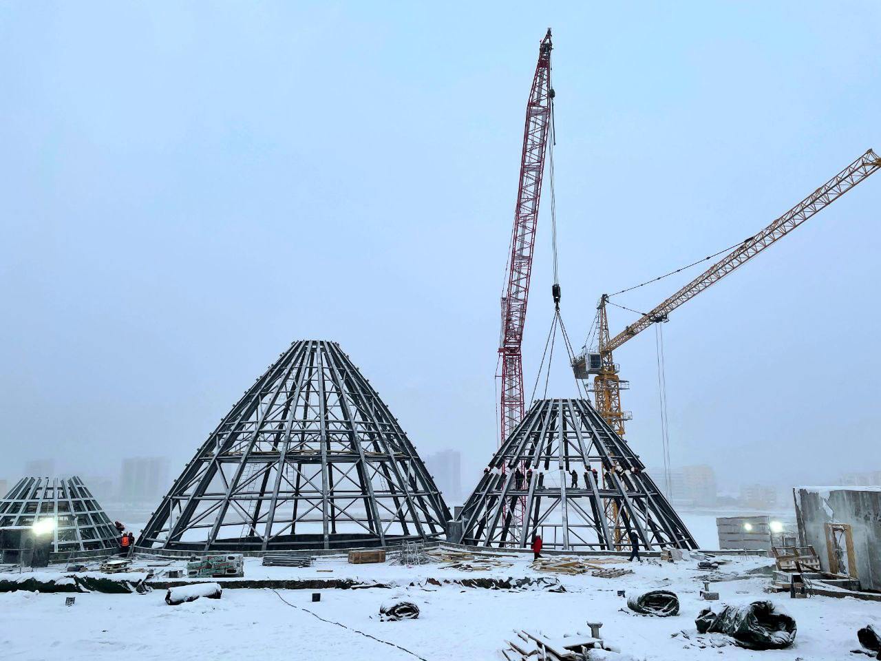 Металлические куполы установили на крыше Арктического центра в Якутске  Каркас здания включает в себя три урасы и светопрозрачный купол в виде озера на крыше. Конструкции весят около 140 тонн, их диаметр - от 15,6 до 27,4 метра. Самая высокая точка центральной урасы - почти 39 метров.  Урасы венчают большой и малый зрительные залы театров, мультимедийный зал. Они отсылают к культуре и быту коренного народа. В целом крыша центра станет зоной для мероприятий и прогулок.   «Здесь появятся сад камней, «стеклянное озеро» и амфитеатр. Общая площадь крыши - более 9000 квадратных метров», - сообщили в правительстве региона.   Арктический центр готов на 70 процентов. Его возводят свыше 235 человек и 12 единиц техники. Сейчас идет укладка внутренних перегородок на семи этажах, штукатурка стен, утепление и гидроизоляция полов. Объект подключен к теплу.  Фото: правительство РС  Я