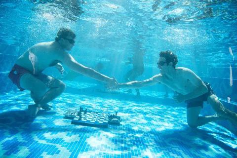 От фирменных пиджаков к фирменным плавкам В преддверии финального турнира Freestyle Chess Grand Slam Tour был организован мини турнир по подводным шахматам В нём приняли участие самые выносливые Фабиано Каруана Видит Гуджрати Жавохир Синдаров и Ханс Ниманн Игрокам раздали форму то есть плавки под цвет их пиджаков Парень в розовых плавках по фамилии Ниманн стал победителем турнира chessgames