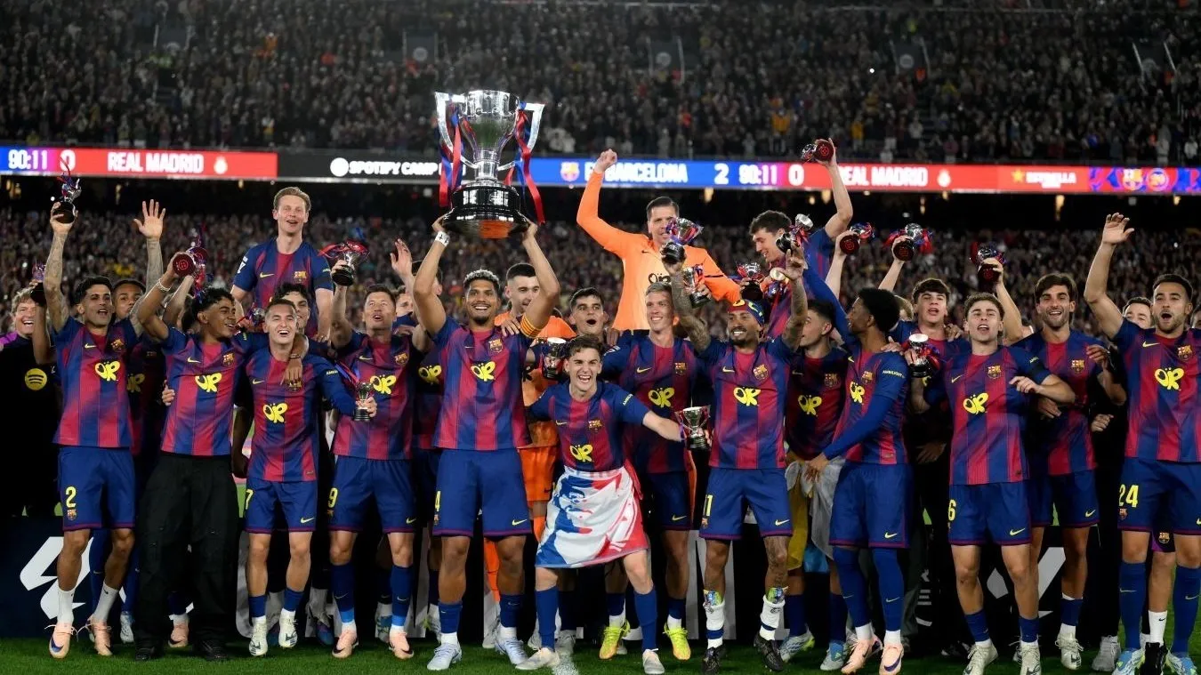 FC Barcelona чемпион Испании В главном матче сезона Барселона обыграла Real Madrid со счётом 2 0 и досрочно оформила титул Ла Лиги прямо на переполненном Camp Nou Каталонцы берут второй чемпионский титул подряд под руководством Hansi Flick Особенно эмоциональным вечер стал из за личной трагедии тренера утром Флик узнал о смерти отца но всё равно вышел на скамейку и привёл команду к победе Для Реала сезон заканчивается провалом без Лиги чемпионов без чемпионства и с серьёзными вопросами к будущему команды Камп Ноу этой ночью превратился в центр праздника всей Каталонии
