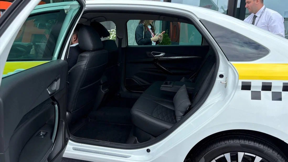 АвтоВАЗ показал Lada Aura для такси АвтоВАЗ выставил на ПМЭФ также новую версию «лимузина» Lada Aura — она получила штатное оформление кузова для такси. Ранее предполагалось, что предприятие будет отправлять в таксопарки упрощённую модификацию седана, но в Санкт-Петербурге показали всё же «богатую» версию. Салон представленного экземпляра оформлен стёганой кожей и укомплектован подушками для задних пассажиров. Кроме того, для них предусмотрен собственный пульт управления подогревами и USB-порты. Судя по двум подголовникам заднего дивана, Aura для такси выполнена на базе максимальной комплектации Status ценой 2 799 000 рублей.