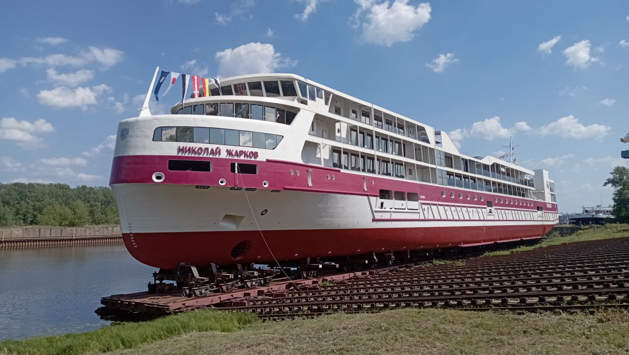 Круизный теплоход «Николай Жарков» спустили на воду на заводе «Красное Сормово»  Судно названо в честь покойного директора, много лет руководившего предприятием. Крестной мамой теплохода, разбившей бутылку шампанского о борт, стала Мария Жаркова, внучка судостроителя.  Выход в эксплуатацию запланирован на весну 2026 года. Ожидается, что в следующем году «Николай Жарков» совершит более 20 круизов, в том числе в Черном, Каспийском, Азовском, Белом и Балтийском морях.  По уровню комфорта теплоход будет соответствовать пятизвездочному отелю, сообщили в «Водоходе». На лайнере предусмотрен открытый бассейн с теплой водой, солярий под открытым небом, амфитеатр и летний кинотеатр.  Стоимость десятидневного тура, например по маршруту Ростов-на-Дону — Махачкала — Астрахань, предлагается от 485 тыс. руб. за человека.  Фото: Роман Кряжев, Коммерсантъ    Подписывайтесь на «Ъ-Приволжье» Оставляйте «бусты»