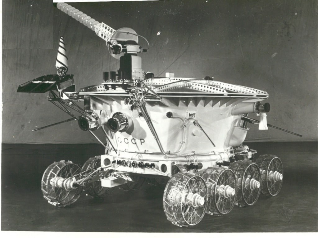 Луноход 1 55 лет первому роботу на Луне 10 ноября1970 года с космодрома Байконура стартовала станция Луна 17 с первым в мире автоматическим самоходным аппаратом Луноходом 1 Через неделю 17 ноября станция совершила мягкую посадку в районе Моря Дождей и луноход съехал на поверхность Луны За 301 сутки аппарат прошёл 10 540 метров мировой рекорд для планетохода Он передал на Землю более 200 лунных панорам около 20 000 фотографий данные о физико механических свойствах грунта информацию о химическом составе реголита кремний железо кальций алюминий магний титан калий Луноход 1 создали в НПО имени С А Лавочкина под руководством Г Н Бабакина шасси разработало ВНИИТрансМаш Аппарат состоял из колёсного шасси и герметичного приборного контейнера с солнечной батареей телефотометрической системой четыре камеры и приборами для исследования грунта Управление велось дистанционно из Центра управления луноходом экипажем из пяти специалистов Миссия установила несколько мировых рекордов подтверждённых Международной авиационной федерацией по продолжительности работы массе аппарата пройденному расстоянию и скорости движения на лунной поверхности Луноход 1 не просто открыл новую эру в исследовании Луны он доказал что автоматические аппараты могут собирать научные данные не менее эффективно чем пилотируемые миссии
