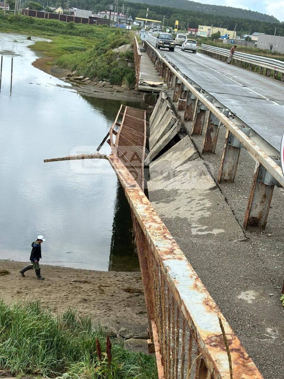 Часть моста обвалилась в Охотском  Пешеходная часть мостового сооружения обвалилась в селе Охотском Корсаковского района. Фото последствий в редакцию astv.ru днём 9 августа прислали очевидцы. Когда конкретно произошло обрушение — не уточняется.  Как стало известно astv.ru, рухнул пешеходный отрезок моста, который соединяет село с пляжной зоной. Судя по снимкам, значительная часть дорожки и перила свисают, что создает угрозу для проходящих под конструкцией людей.  Информации о пострадавших нет.