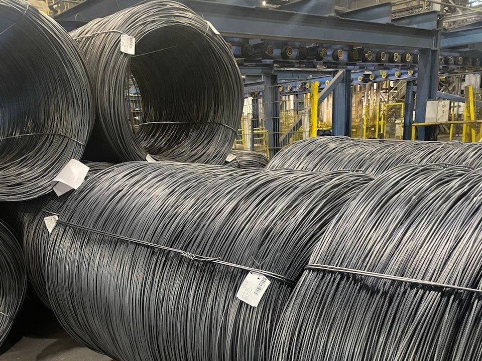 Металлурги помогут строителям сэкономить на арматуре Компания Промсорт Урал Свердловская область один из крупнейших производителей сортового проката и метизов впервые в России выпустила партию горячекатаной термически упрочненной арматуры диаметром 5 мм Это пока минимальный диаметр прутков освоенный отечественной металлургической промышленностью в продвинутом классе стали А500С Применение нового вида продукции будет способствовать сокращению стоимости строительно монтажных работ за счет снижения металлоемкости До сих пор российские металлурги производили горячекатаный сортовой прокат диаметром не менее 6 мм тогда как в мировой практике уже достигнута планка в 4 мм Соответственно у нас тонкие прутки в том числе диаметром 5 мм получали только методом холодной деформации Между тем фаворитом современной стройки является именно горячекатаная арматура на ее долю приходится до 70 мирового рынка поскольку она обладает большей прочностью и пластичностью устойчивостью к механическим нагрузкам и коррозии Данных по структуре рынка в России нет но так или иначе мы находимся в общем тренде Особенно это актуально для развивающихся экономик где массово возводятся масштабные объекты инфраструктуры из железобетона плотины мосты тоннели фундаменты дороги производственнные предприятия жилые монолитные дома Благодаря высоким прочностным характеристикам горячекатаной арматуры диаметр прутков при использовании их в производстве железобетона может быть меньше чем в случае холоднокатаных Помимо снижения металлоемкости стройки это уменьшает вес железобетонных плит затраты на их траспортировку и монтаж Впрочем при использовании горячекатаной арматуры уменьшение диаметра прутка на 1 мм тоже дает заметную экономию на металле Парадоксально на первый взгляд но переход на горячую прокатку с термоупрочнением оптимизирует затраты и самого производителя арматуры Несмотря на то что эта технология сложнее чем холодная деформация поскольку включает в себя нагрев заготовок до температуры 1000 1250 градусов а также закалку прокатанной арматуры она в то же время обходится без многих других промежуточных операций В итоге сокращается производственный цикл и следовательно себестоимость конечной продукции Что касается инвестиций в модернизацию производства под выпуск нового диаметра прутка то проект Промсорт Урала осуществлен за счет внутренних ресурсов Как сообщает пресс служба специалисты предприятия самостоятельно разработали новую калибровку и построили оригинальную схему нарезки калибров Схема нарезки калибров или план рельефов арматурного профиля который наносят на прокатные валки принципиально важен от него зависит качество сцепления арматуры с бетоном Также своими силами подобрали и заказали режущий инструмент выполнили нарезку прокатных шайб С помощью данного проекта Промсорт Урал пытается решить важную тактическую задачу не допустить снижения продаж на фоне общего падения рынка арматуры обусловленного резким замедлением жилищного строительства Годовой объем выпуска Промсорт Урала 2 млн т составляет 25 общероссийского а по данным Росстата за первое полугодие 2025 года производство арматуры снизилось на 6 год к году Восстановление спроса ожидается не ранее 2026 2027 годов да и то при условии снижения ключевой ставки до 10 12 При этом развитие продуктового портфеля в соответствии с мировым вектором выводит компанию и на новый стратегический виток Речь идет о повышении ее конкурентоспособности на внешних рынках Последнее время экспорт российской арматуры бурно растет главным образом в страны СНГ 62 объема Ближнего Востока и Африки 31 За 9 месяцев 2025 года объем экспорта вырос на 60 в натуральном выражении до 2 5 млн т и по прогнозам в 2026 году двузначные темпы роста сохранятся Вера Краснова Монокль главное о русском бизнесе и не только Подписаться