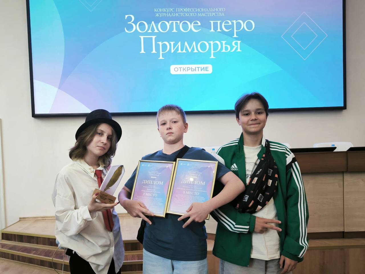 Уссурийские юнкоры одержали  2 победы!  6 июня подвели итоги конкурса для молодых журналистов и блогеров 14-25 лет «Золотое перо Приморья — Открытие»  12+ . 224 заявки в 11 номинациях конкурса.  Свои награды за всю медиакоманду наставника Ульяны Жиулло получили 3 представителя  на фото .   1 место в номинации «Видеоролик года. Школьники» социальный ролик «ПримПоиск».  2 место в номинации «Видеосюжет года. Школьники»  сюжет про участие во Всероссийской акции «Добро пожаловать в семью».  «Очень понравилось, когда мы выходили и нам жали руку. Было интересно и на мастер-классах. Не терпится применить это все на практике!»  - Евгений Губко.  «Еда вкусная, призы в магазин техники - крутые»  - Артемий Швец.  «Забрали 2 статуэтки и грамоты.  Хотя после такого события, общения с интересными людьми, даже без наград мы бы ушли счастливыми» - Софья Козлова.  Организатор конкурса Приморское краевое отделение Союза журналистов России при поддержке Правительства Приморского края и ВВГУ.
