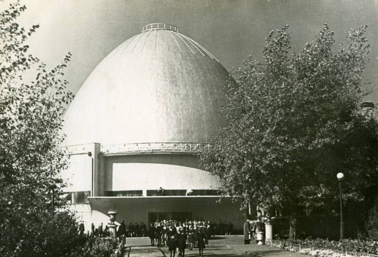 Календарь архитектуры 23 сентября 1928 года в Москве началось строительство Планетария первого в Советском Союзе и тринадцатого в мире научно просветительного учреждения подобного рода Для молодой страны это был символический шаг архитектура и инженерия служили формированию нового научного мировоззрения Сердцем будущего Планетария стал проекционный аппарат Планетарий позволявший создавать точнейшую проекцию звёздного неба на внутреннюю поверхность купола Эта технология производила на современников неизгладимое впечатление как прикосновение к космосу не покидая центра Москвы Архитектурный проект разработанный Михаилом Осиповичем Барщом и Михаилом Исааковичем Синявским стал выдающимся примером советского конструктивизма Пластика здания была подчинена символике строгий параллелепипед увенчанный ротондой с куполом олицетворял гармонию земли и неба материального и космического С самого открытия Планетарий был ориентирован на просветительскую миссию Здесь создавались лекционные программы для школьников и студентов формировалась специализированная библиотека по астрономии Во дворе была построена обсерватория что сделало комплекс не только зрелищным но и подлинно научным центром Строительство продлилось чуть более года торжественное открытие состоялось в ноябре 1929 Московский Планетарий стал ключевым образовательным пространством страны знакомящим миллионы людей с тайнами Вселенной Однако к концу XX века здание нуждалось в серьёзной реконструкции в 1994 году Планетарий был закрыт Масштаб обновления оказался поистине грандиозным Под руководством архитектора Александра Викторовича Анисимова было принято решение приподнять историческое здание на 6 метров чтобы создать новые функциональные пространства Вес сооружения около 3000 тонн был поднят с помощью гидравлических домкратов Этот инженерный подвиг стал уникальным для мировой строительной практики и вошёл в историю как пример технической смелости и мастерства После завершения реконструкции Планетарий превратился в современный многофункциональный комплекс включающий музейные залы интерактивные экспозиции и одну из самых совершенных проекционных систем в мире Сегодня он объединяет прошлое и будущее сохраняя дух конструктивизма и одновременно предлагая новые форматы научного просвещения