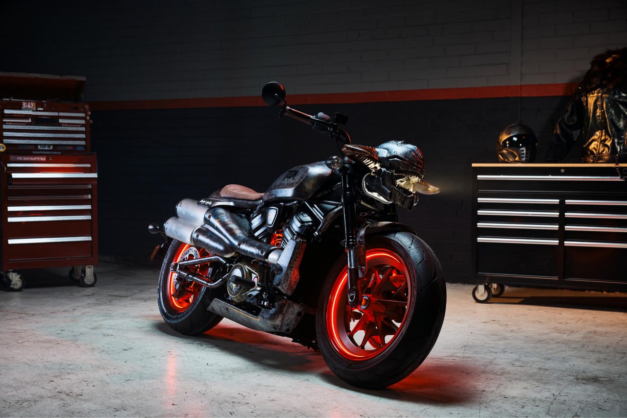 122-сильный «адский байк» из Doom: Harley-Davidson и Bethesda создали уникальный мотоцикл В нем сложно узнать серийный Harley-Davidson Sportster S Bethesda и Harley-Davidson представили эксклюзивный мотоцикл, вдохновлённый грядущей игрой Doom: The Dark Ages. Этот единственный в своём роде байк, основанный на модели Sportster S, переносит средневековый хаос и демоническую эстетику культовой серии Doom на дороги. Мотоцикл максимально соответствует стилистике игры. Фара интегрирована в «пасть» механического дракона Серата — нового персонажа Doom: The Dark Ages: по задумке, так создается эффект огнедышащего зверя. Мотоцикл украшен доспехами, рунами и светодиодной подсветкой, включая красные колёса, напоминающие RGB-вентиляторы игровых ПК. Предусмотрена даже проекция «крыльев дракона» на дорогу. Логотип Doom: The Dark Ages гордо красуется на боковой части. «Создание мотоцикла для Doom: The Dark Ages с Harley-Davidson — это союз, рождённый в аду. Harley-Davidson славится мощью и стилем, как наш легендарный Палач Рока. Этот меха-дракон на колёсах — идеальный способ отметить запуск новой главы Doom», — заявил Саймон Алти, вице-президент Bethesda Softworks. Байк дополнен стильным тематическим комплектом экипировки: чёрной кожаной курткой с шипами и пушистым воротником, а также шлемом с красным визором и «ирокезом» в духе Doom. Купить мотоцикл не получится: единственный экземпляр будет разыгран на мероприятии, посвящённом запуску Doom: The Dark Ages, которое пройдёт 16 мая 2025 года с 19:00 до 21:00 в Culture Kings на Джордж-стрит в Сиднее, Австралия. Сама игра Doom: The Dark Ages выходит 13 мая. Harley-Davidson Sportster S оснащается 1,25-литровым мотором Revolution Max 1250T с электронной системой зажигания, мощность составляет 122 л.с.