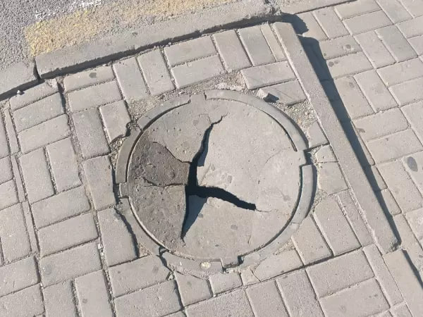 Канализационный люк потрескался на улице Максима Горького 97/49 в Ростове.  Жители выражают обоснованную озабоченность по поводу потенциальной угрозы падения кого-либо в открытый люк.