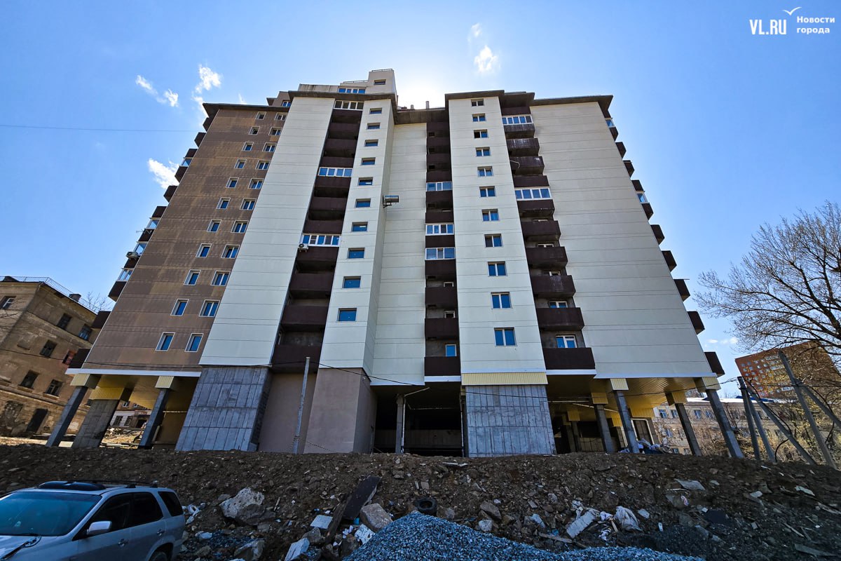 Жители ЖК "Сафонов" во Владивостоке продолжают жить в недостроенном доме Спустя полтора года после "сдачи" жилой части ЖК "Сафонов" жители до сих пор вынуждены заходить через пожарный выход, сталкиваться с протечками и отсутствием благоустройства. Несмотря на выделенные 70 млн рублей, нежилая часть дома парковка, парадный вход остаётся недостроенной, а подрядчики отказываются работать из-за недостаточного финансирования. Жильцы самостоятельно убирают строительный мусор,в доме протекает крыша, затапливая лифт и верхние этажи, подъезды не отделаны, коммуникации оголены, парковка превратилась в свалку. Сроки окончания работ переносят, а жители, уже оплачивающие коммунальные услуги, вынуждены мириться с условиями "временного" проживания.